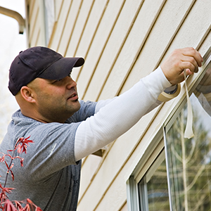 a painter removing tape from a house exterior